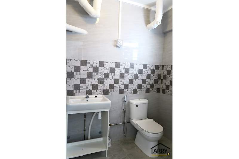 Bathroom with a patterned tile band, white basin, new toilet and exposed pipework painted white - HDB resale flat renovation with polished terrazzo floors, new kitchen and bathrooms (C04) | Larry Contractors, HDB Licensed Renovation Contractor, Singapore