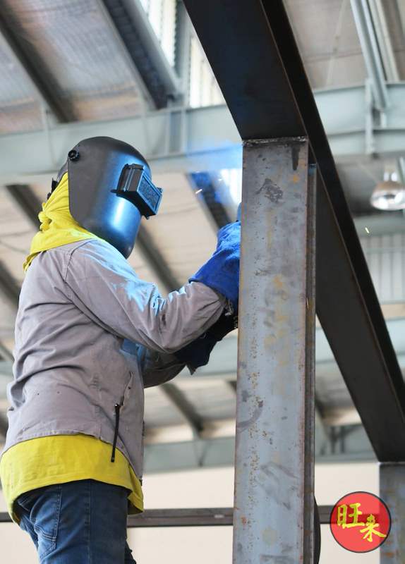 During works: a welder in a face shield welding a steel column joint - Heavy-duty cable drum racking in a cable yard (TSE) | Larry Contractors, HDB Licensed Renovation Contractor, Singapore