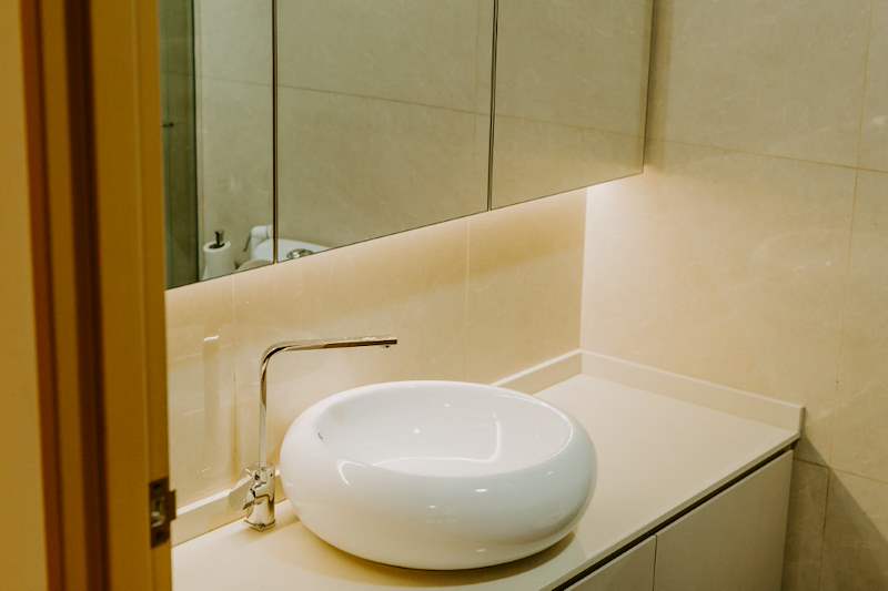 Bathroom vanity with a round white countertop basin, a chrome mixer tap and a lit mirror cabinet - HDB flat renovation in cream and mirror-trim laminate with a galley kitchen (C10) | Larry Contractors, HDB Licensed Renovation Contractor, Singapore