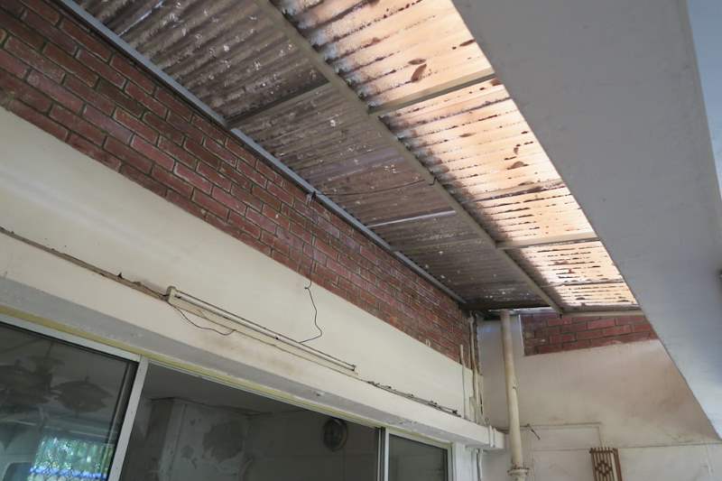 Before: rusted corrugated cladding under the external beam above the windows, brick wall exposed - HDB flat renovation with a new kitchen, false ceiling and repaired cladding (320WS) | Larry Contractors, HDB Licensed Renovation Contractor, Singapore