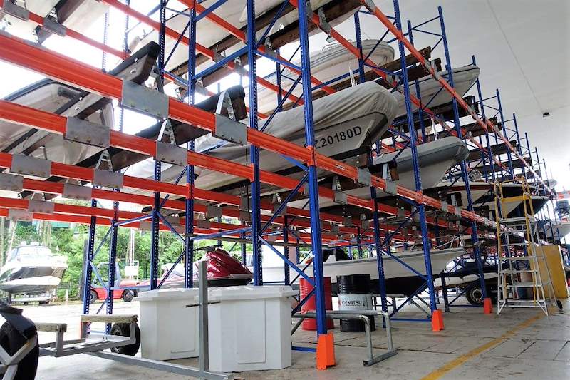 Line of racking bays with boats on every tier, an access ladder and floor markings below - Heavy-duty storage racking for boats and jet skis (Sentosa) | Larry Contractors, HDB Licensed Renovation Contractor, Singapore