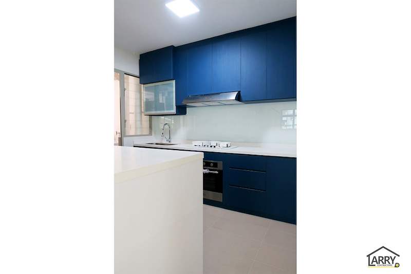 Blue and white kitchen with a cooker hood, glass splashback and a built-in oven under the hob - HDB flat renovation with a platform bay window seat and blue kitchen (C20) | Larry Contractors, HDB Licensed Renovation Contractor, Singapore