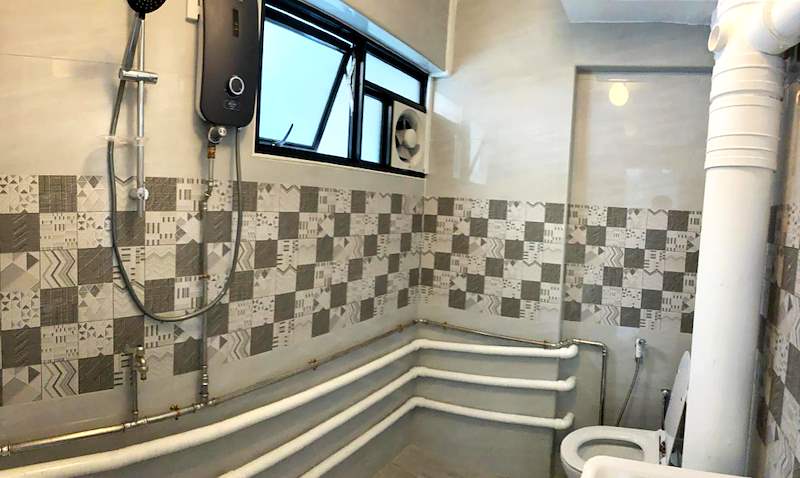 Shower with an instant water heater above a patterned tile band, pipework painted white - HDB resale flat renovation with polished terrazzo floors, new kitchen and bathrooms (C04) | Larry Contractors, HDB Licensed Renovation Contractor, Singapore