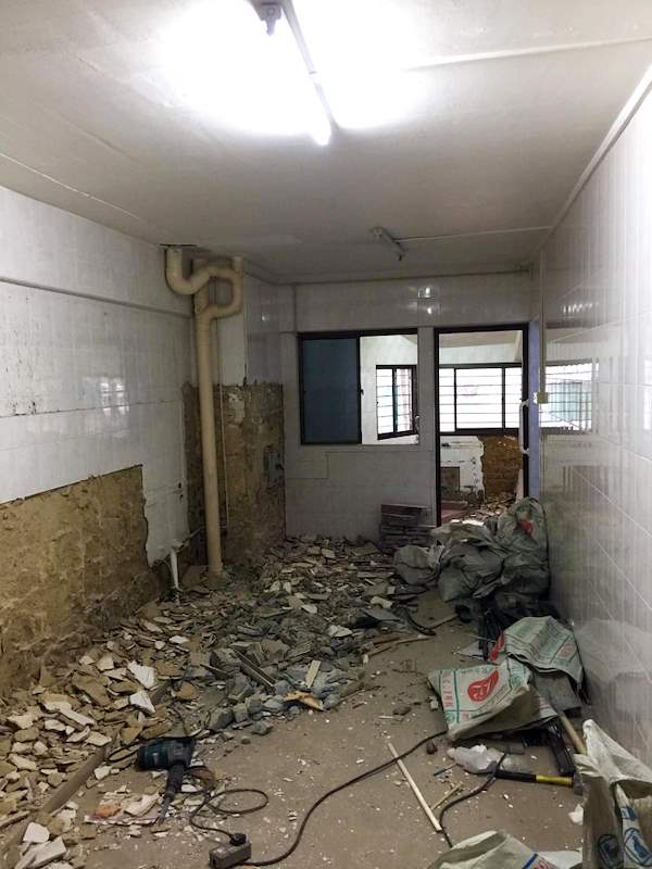 During demolition: the kitchen stripped out with debris on the floor and exposed pipes - HDB resale flat renovation with polished terrazzo floors, new kitchen and bathrooms (C04) | Larry Contractors, HDB Licensed Renovation Contractor, Singapore