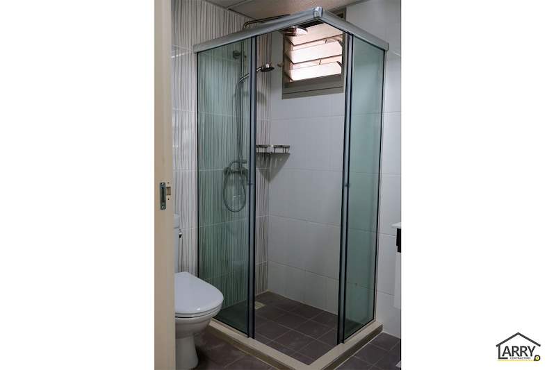 After: bathroom with a glass shower screen, rain shower and new wall tiles - HDB flat renovation with a platform bay window seat and blue kitchen (C20) | Larry Contractors, HDB Licensed Renovation Contractor, Singapore
