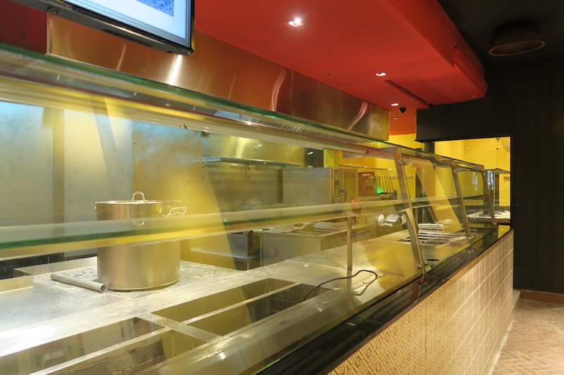 Glass-fronted stainless steel serving counter with pots on the cooking line behind - Restaurant fit-out with an open kitchen counter and marble frontage (C48) | Larry Contractors, HDB Licensed Renovation Contractor, Singapore