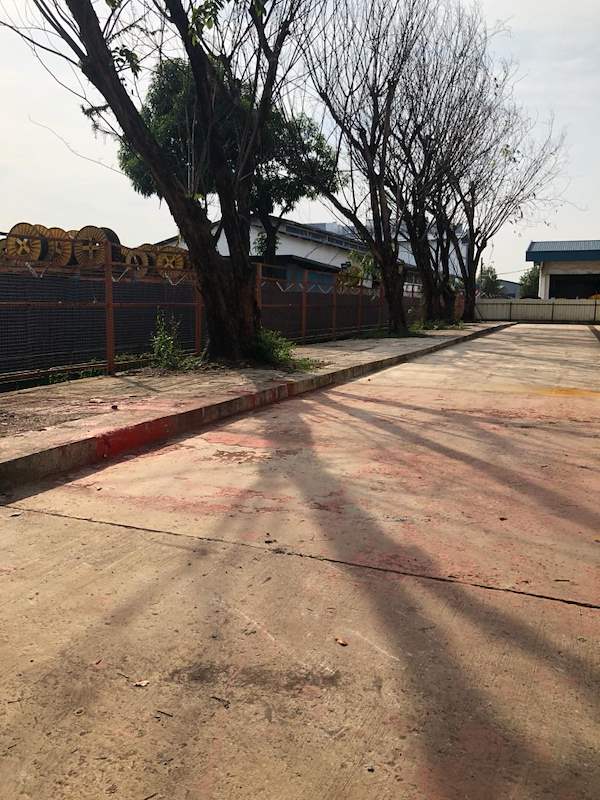 Before: the open yard beside the shed with a bare concrete apron and trees along the fence - Heavy-duty cable drum racking in a cable yard (TSE) | Larry Contractors, HDB Licensed Renovation Contractor, Singapore