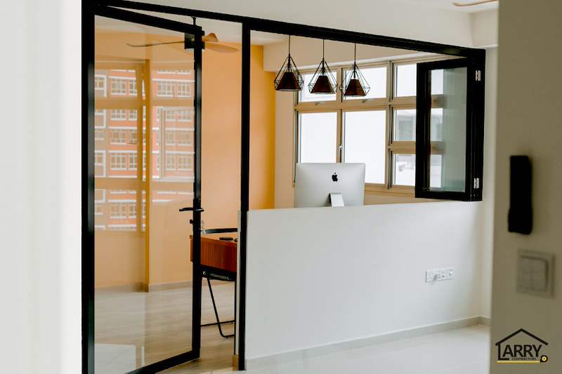 Black-framed glass partition with a half-height wall enclosing the study, desk and computer inside - HDB flat renovation with a glass-partitioned study, hidden shoe cabinet and navy kitchen (442BB) | Larry Contractors, HDB Licensed Renovation Contractor, Singapore