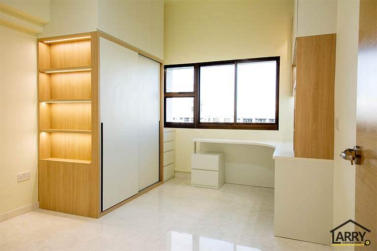Bedroom with a lit display cabinet, sliding-door wardrobe and a built-in corner study desk at the window - HDB flat renovation with full-height carpentry and a wood-tone kitchen (C12) | Larry Contractors, HDB Licensed Renovation Contractor, Singapore