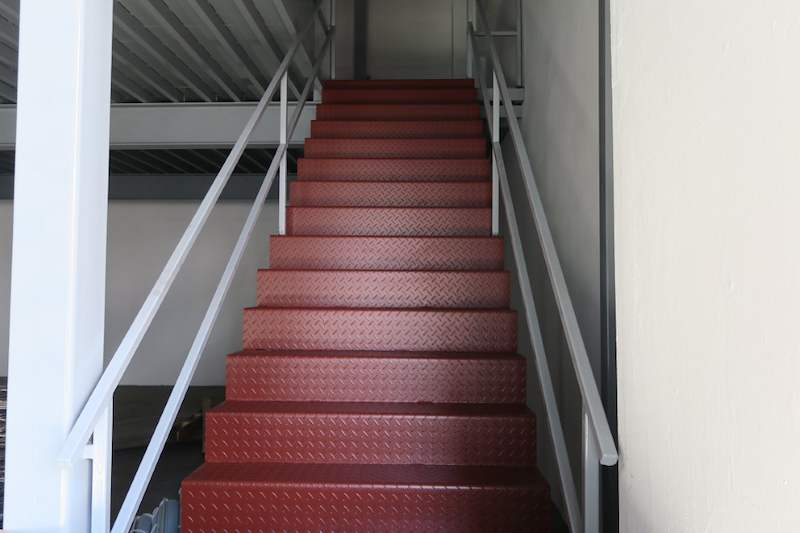 Staircase with red checker-plate treads and grey pipe handrails up to the mezzanine - Two-level steel mezzanine with staircases in an industrial unit (HF0107) | Larry Contractors, HDB Licensed Renovation Contractor, Singapore