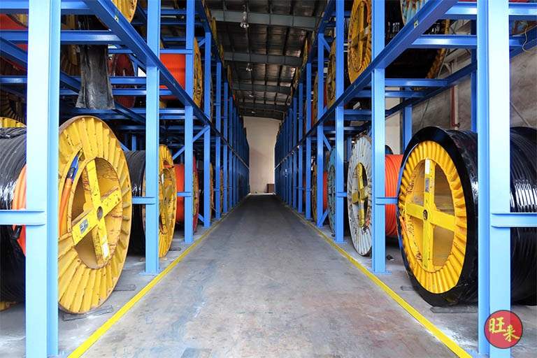 After: the aisle between two rows of blue racking stacked with cable drums under the shed roof - Heavy-duty cable drum racking in a cable yard (TSE) | Larry Contractors, HDB Licensed Renovation Contractor, Singapore