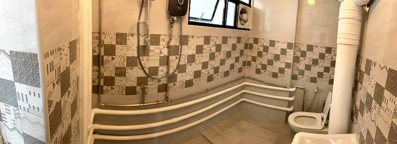 Bathroom after renovation with a patterned tile band, new toilet and exposed pipework painted white - HDB resale flat renovation with polished terrazzo floors, new kitchen and bathrooms (C04) | Larry Contractors, HDB Licensed Renovation Contractor, Singapore