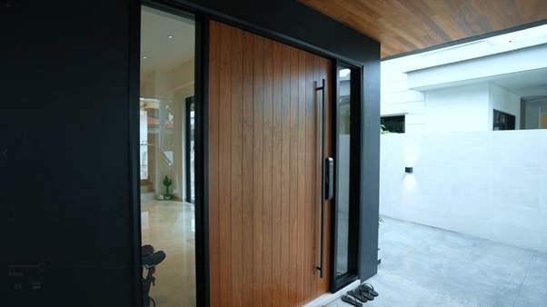 Timber pivot front door with a black frame and glass side panel at the entrance - Landed house renovation with new facade, staircase and interiors (39EW) | Larry Contractors, HDB Licensed Renovation Contractor, Singapore