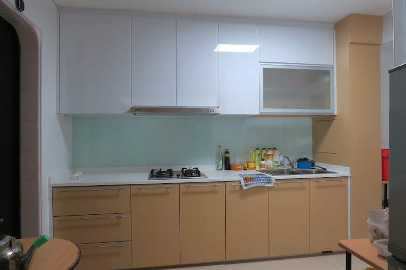After: kitchen with white upper cabinets, beige laminate lower cabinets, a glass splashback and cooker hood - HDB flat renovation with a new kitchen, false ceiling and repaired cladding (320WS) | Larry Contractors, HDB Licensed Renovation Contractor, Singapore