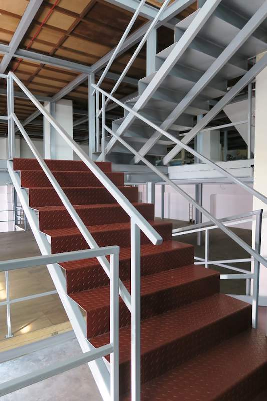 Red checker-plate stair treads and grey pipe railings on the mezzanine staircase - Two-level steel mezzanine with staircases in an industrial unit (HF0107) | Larry Contractors, HDB Licensed Renovation Contractor, Singapore