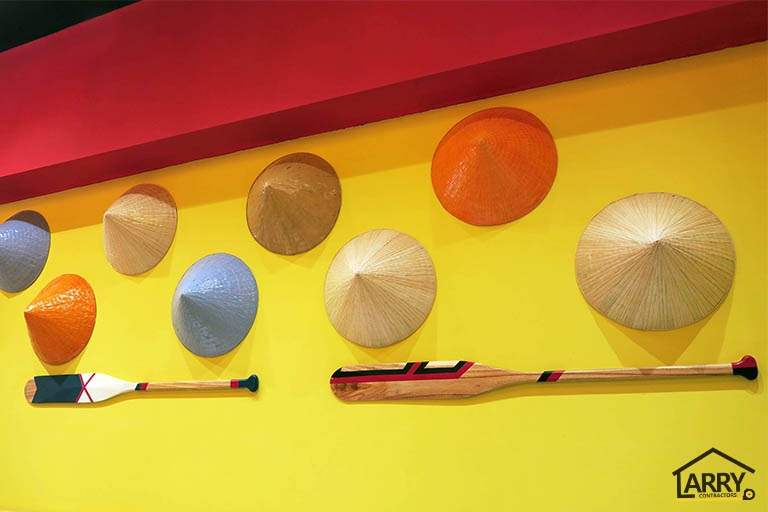 Yellow feature wall with conical hats and two timber oars mounted under a red bulkhead - Restaurant fit-out with an open kitchen counter and marble frontage (C48) | Larry Contractors, HDB Licensed Renovation Contractor, Singapore