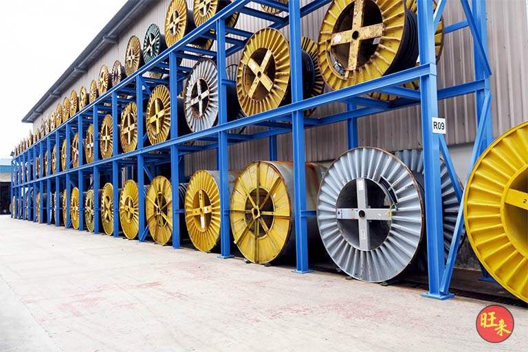 Long run of blue two-tier steel racking loaded with cable drums, seen from the end of the row - Heavy-duty cable drum racking in a cable yard (TSE) | Larry Contractors, HDB Licensed Renovation Contractor, Singapore