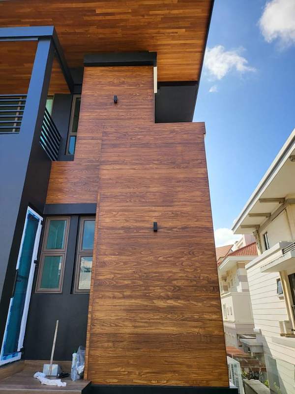 Looking up at the timber cladding and dark panels of the new facade against the sky - Landed house renovation with new facade, staircase and interiors (39EW) | Larry Contractors, HDB Licensed Renovation Contractor, Singapore